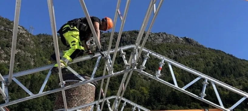 Stillasmontør i hjelm og vernetøy på toppen av et tak over tak i Sandviken